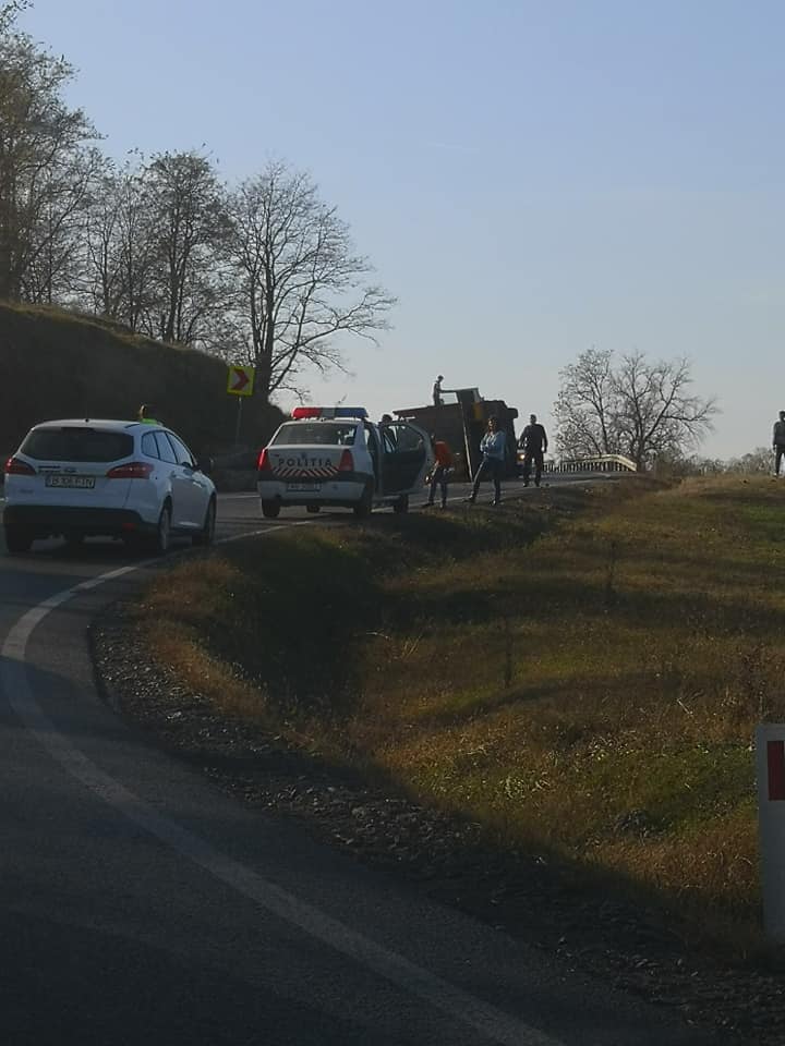 FOTO și VIDEO – TIR plin cu lemne răsturnat pe DN 14. Mai mulți bușteni au ajuns pe o mașină