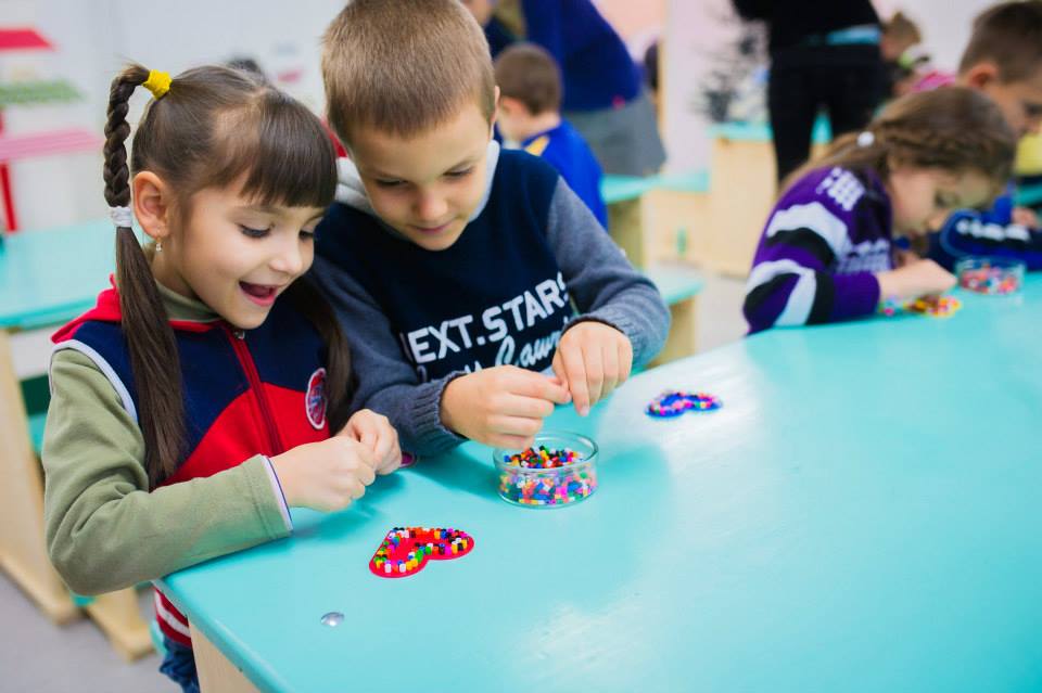 Copiii confecţionează decoraţiuni de brad cu ajutorul pieselor termoadezive, la Târgul de Crăciun