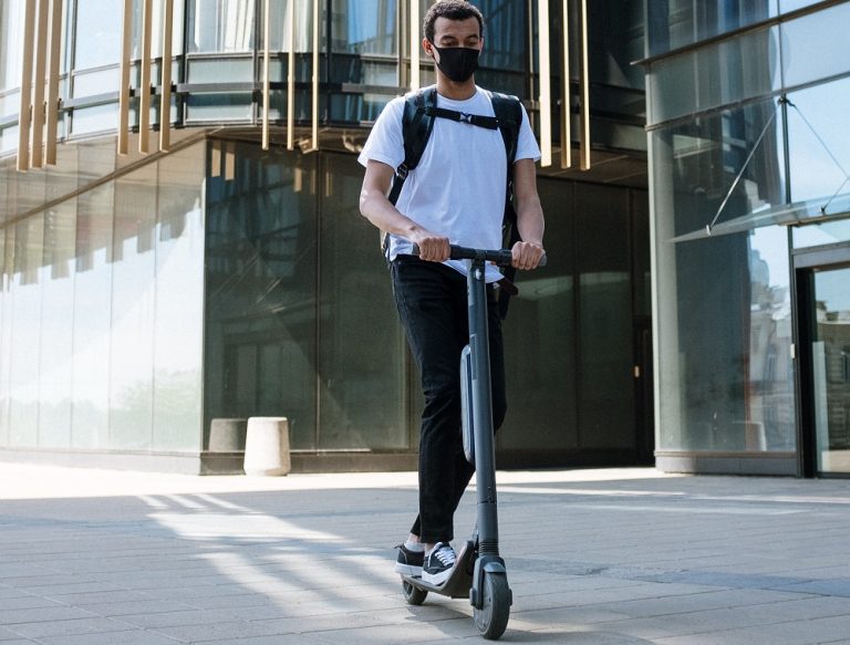 Un tânăr pe trotinetă, acroșat de o portieră deschisă